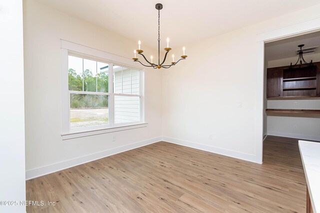 empty room with hardwood / wood-style floors and a notable chandelier