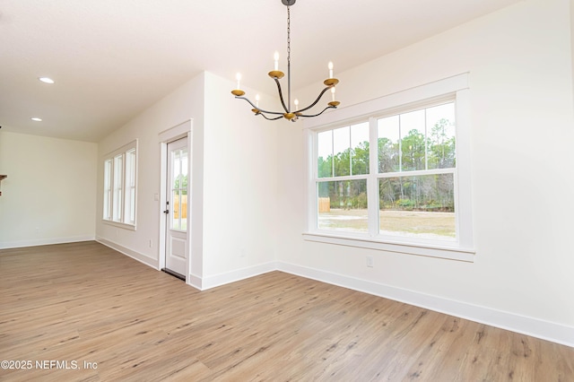 empty room featuring light wood-type flooring and an inviting chandelier