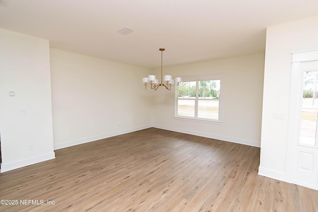 unfurnished room featuring hardwood / wood-style floors and a chandelier