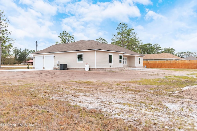 rear view of property with central air condition unit and a garage