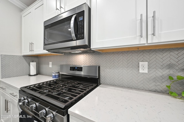 kitchen featuring light stone countertops, appliances with stainless steel finishes, backsplash, and white cabinetry