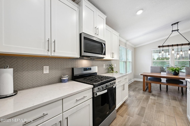 kitchen featuring white cabinets, light stone counters, hanging light fixtures, and appliances with stainless steel finishes