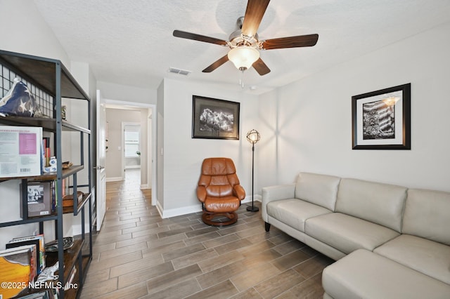 living room with a textured ceiling and ceiling fan