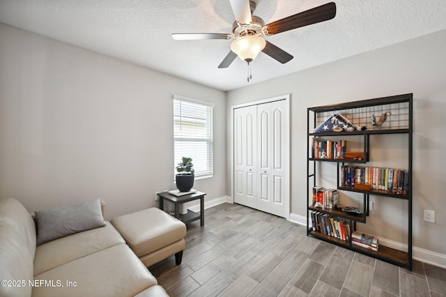 living area featuring hardwood / wood-style flooring, a textured ceiling, and ceiling fan