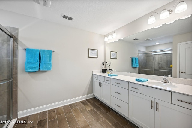 bathroom with a textured ceiling, walk in shower, and vanity