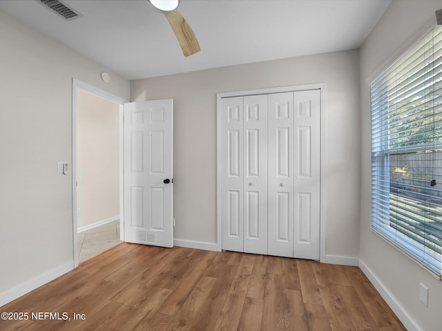 unfurnished bedroom featuring ceiling fan, a closet, and light wood-type flooring