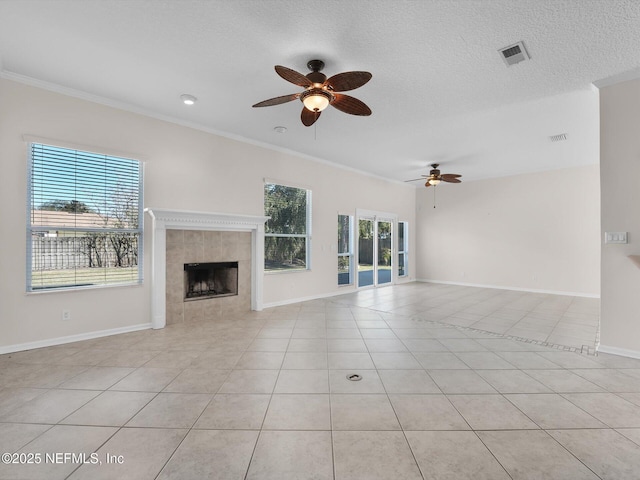 unfurnished living room with light tile patterned flooring, a fireplace, ceiling fan, crown molding, and a textured ceiling