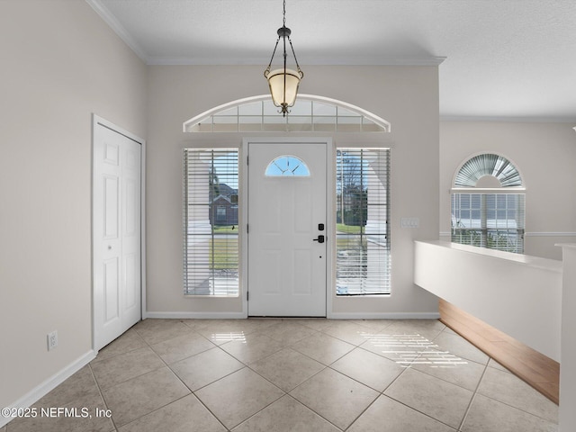 tiled foyer featuring crown molding and plenty of natural light