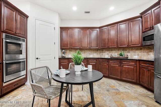 kitchen with dark stone countertops, appliances with stainless steel finishes, and backsplash