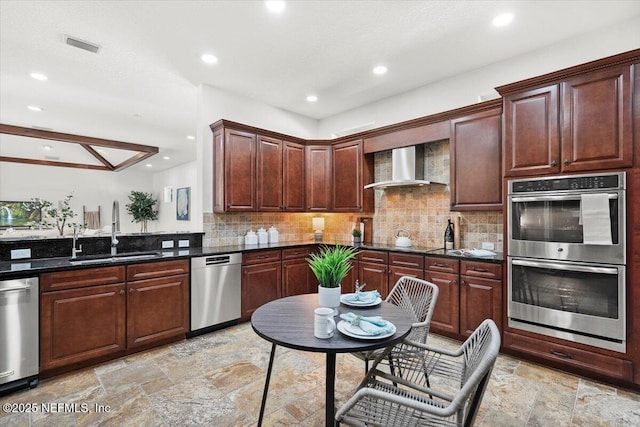 kitchen featuring sink, dark stone countertops, stainless steel appliances, decorative backsplash, and wall chimney exhaust hood