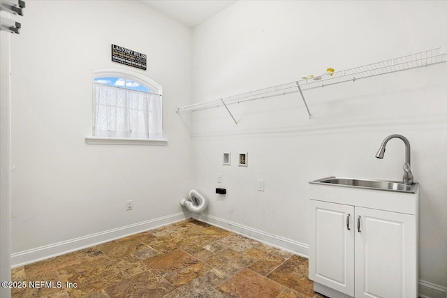 laundry room featuring cabinet space, baseboards, stone finish floor, hookup for a washing machine, and a sink