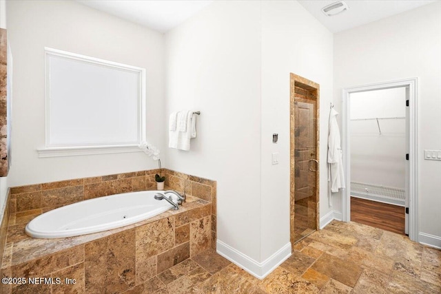 full bath featuring visible vents, a spacious closet, a bath, a stall shower, and stone tile flooring