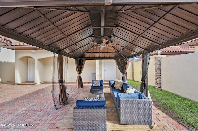 view of patio / terrace with fence, an outdoor hangout area, a ceiling fan, and a gazebo