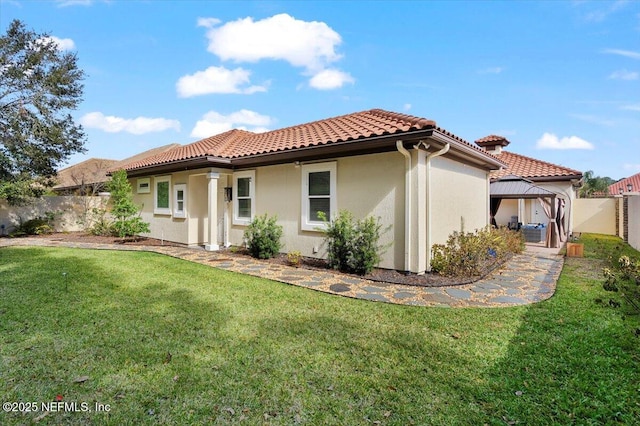 back of house featuring a gazebo, a yard, and a tiled roof