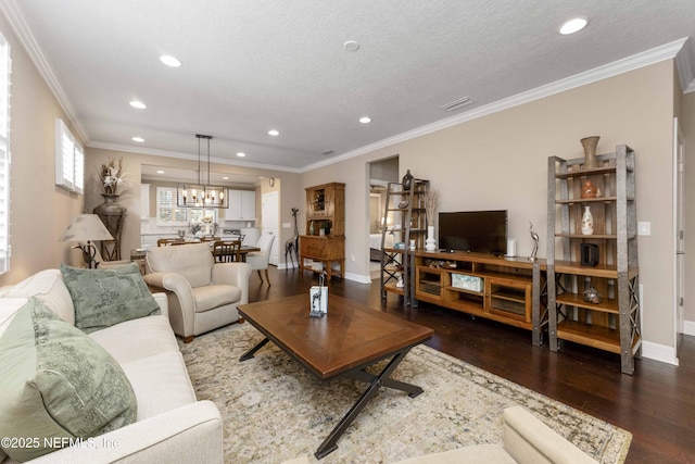 living room featuring a notable chandelier, ornamental molding, dark hardwood / wood-style floors, and a textured ceiling