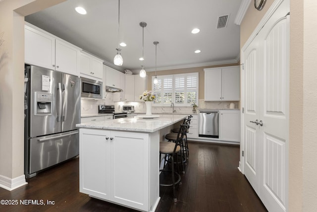 kitchen featuring pendant lighting, white cabinetry, a center island, and appliances with stainless steel finishes