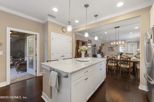 kitchen with light stone counters, decorative light fixtures, a center island, stainless steel refrigerator, and white cabinets