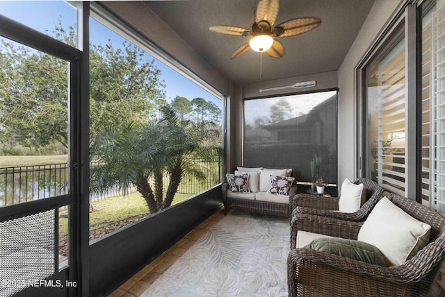 sunroom with a water view, a wealth of natural light, and ceiling fan