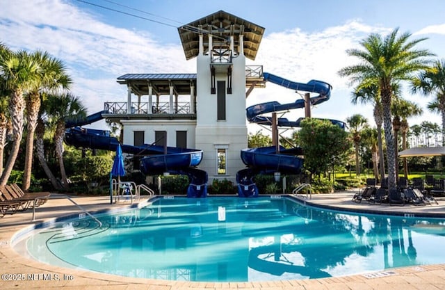 view of swimming pool with a water slide and a patio