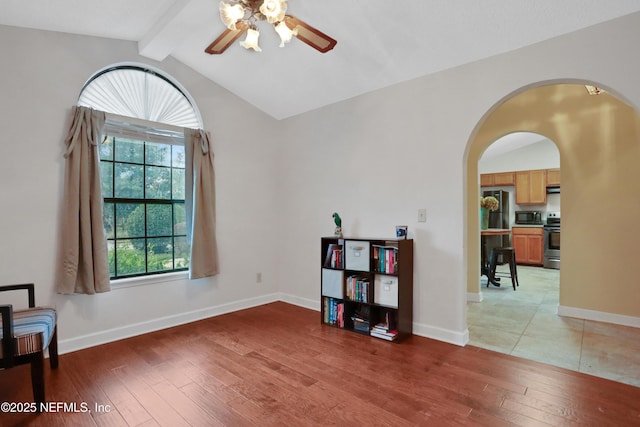 interior space featuring hardwood / wood-style flooring, vaulted ceiling with beams, ceiling fan, and a healthy amount of sunlight