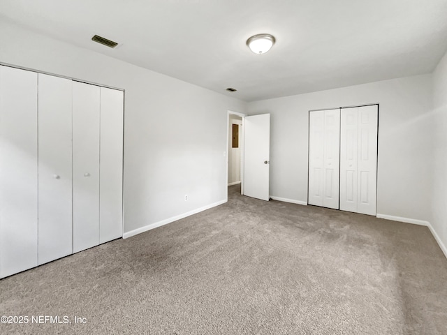 unfurnished bedroom featuring carpet floors and multiple closets