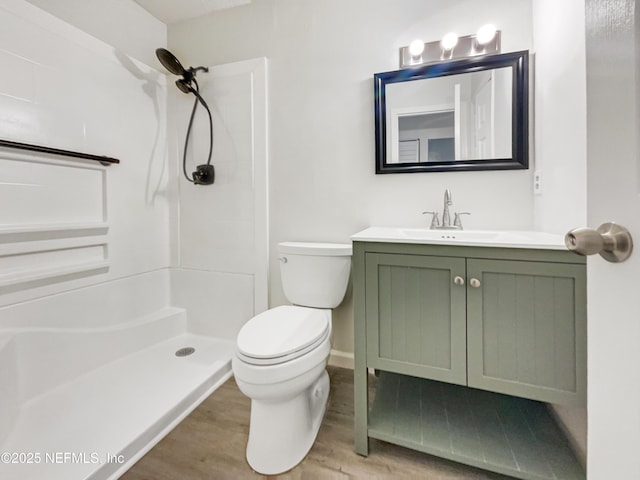 bathroom with hardwood / wood-style floors, toilet, vanity, and walk in shower