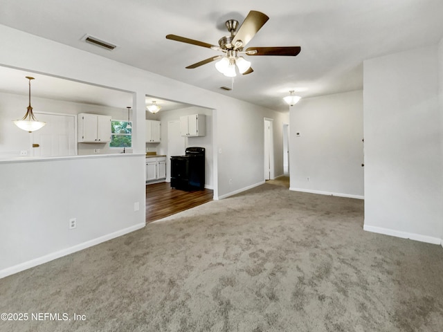 unfurnished living room featuring ceiling fan and dark colored carpet