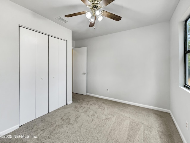 unfurnished bedroom featuring ceiling fan, light colored carpet, and a closet