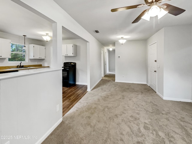 unfurnished living room featuring ceiling fan, sink, and carpet flooring