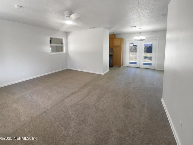 unfurnished living room featuring a textured ceiling, french doors, carpet, and ceiling fan with notable chandelier