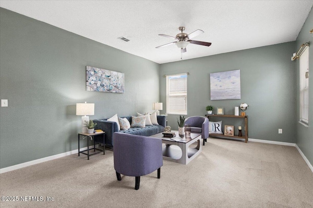 carpeted living room featuring ceiling fan and a textured ceiling