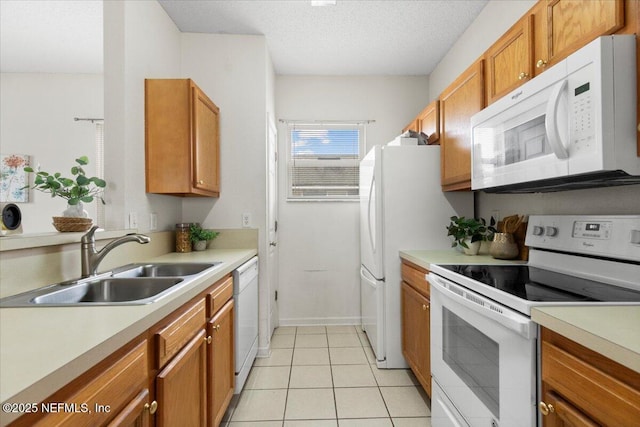 kitchen featuring white appliances, light tile patterned flooring, sink, and a textured ceiling