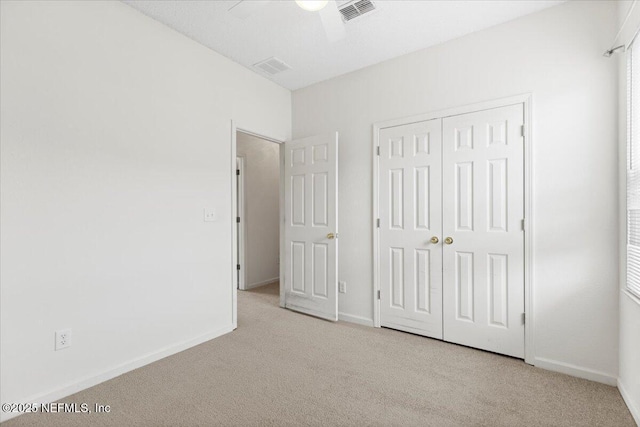 unfurnished bedroom featuring ceiling fan, a closet, and light carpet