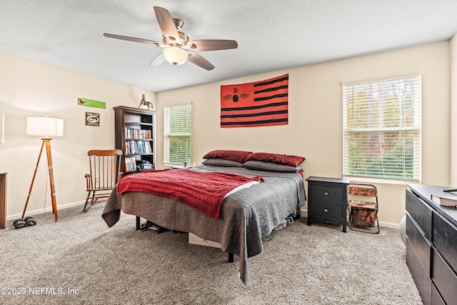 carpeted bedroom with ceiling fan, multiple windows, and a textured ceiling