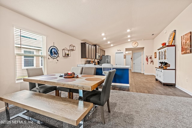 dining room with vaulted ceiling and light wood-type flooring