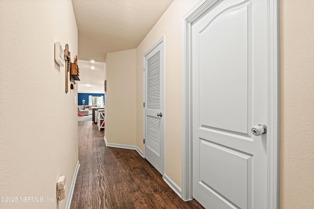 hall featuring dark wood-type flooring and a textured ceiling