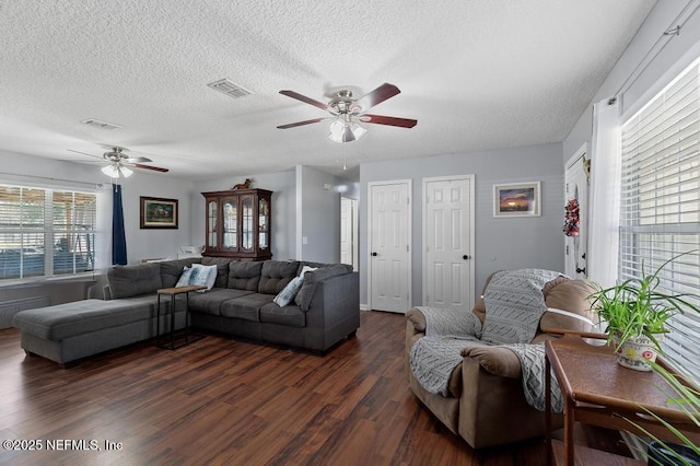 living room featuring ceiling fan, dark hardwood / wood-style floors, and a textured ceiling