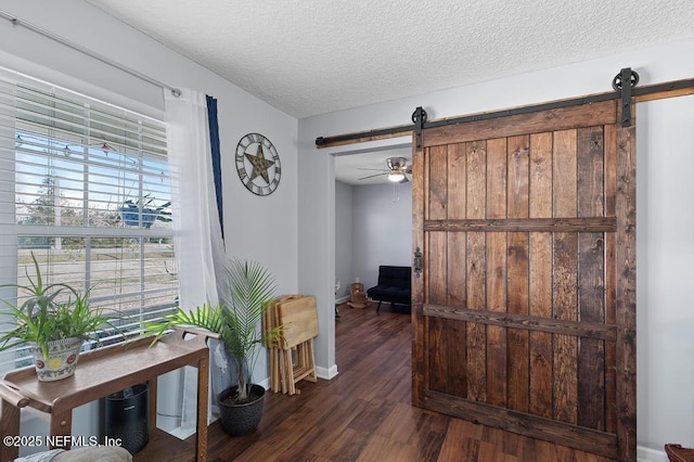 hall with dark wood-type flooring, a textured ceiling, and a barn door