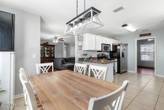 tiled dining space with ceiling fan and a textured ceiling