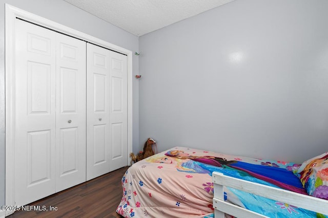 bedroom featuring dark wood-type flooring, a textured ceiling, and a closet