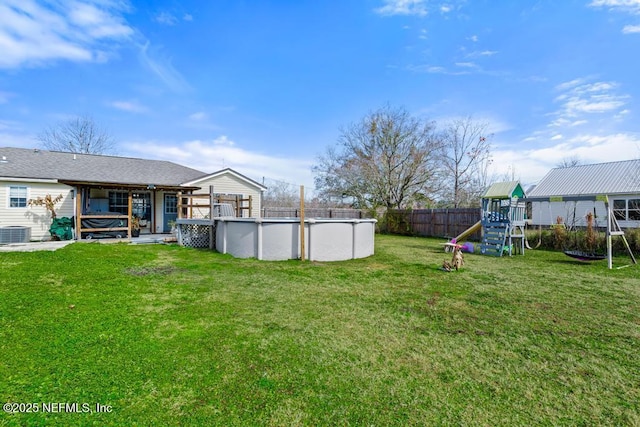 view of yard with a playground, a fenced in pool, and central AC unit