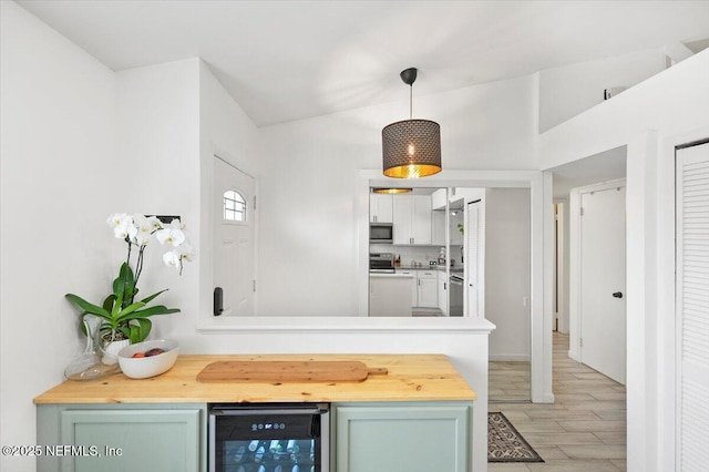 kitchen with wooden counters, wine cooler, hanging light fixtures, kitchen peninsula, and green cabinets