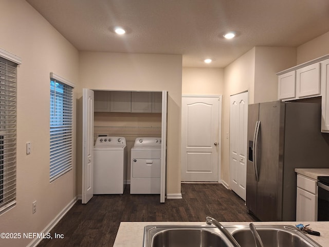 kitchen with stainless steel fridge with ice dispenser, dark hardwood / wood-style flooring, sink, white cabinetry, and washing machine and clothes dryer