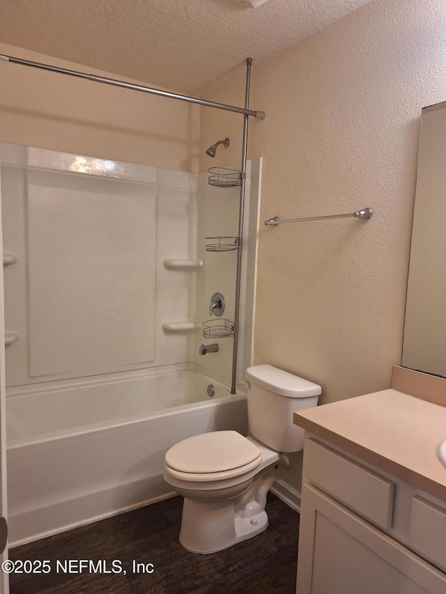 full bathroom featuring toilet, a textured ceiling, bathtub / shower combination, wood-type flooring, and vanity