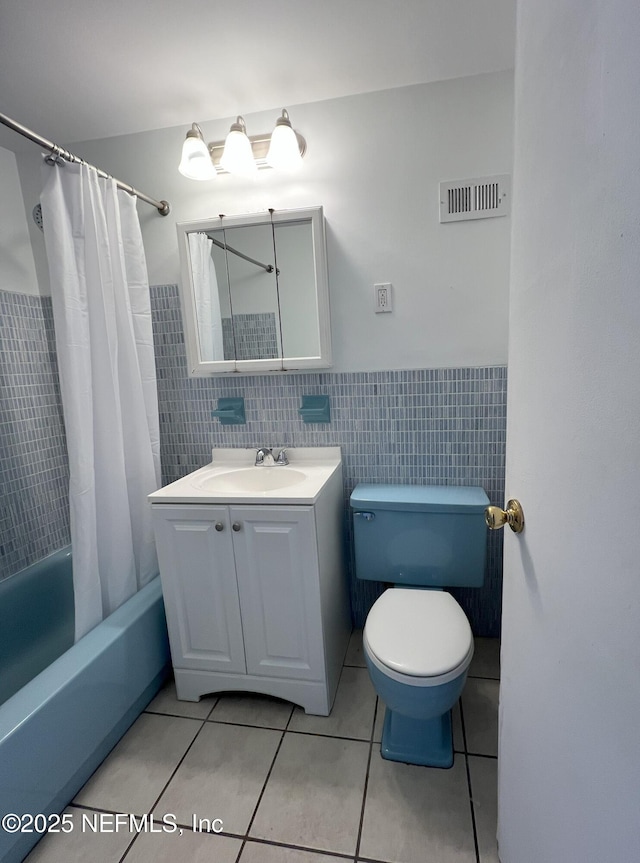 full bathroom with tile patterned flooring, toilet, vanity, tile walls, and shower / tub combo with curtain