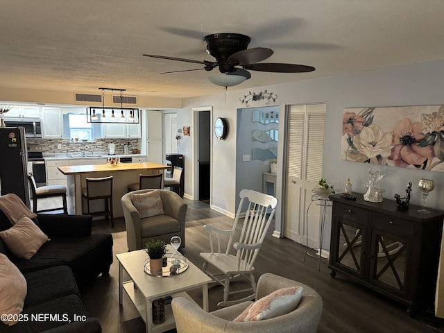 living room featuring dark hardwood / wood-style flooring, sink, and ceiling fan with notable chandelier