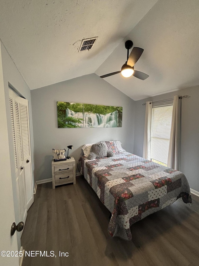 bedroom featuring a textured ceiling, dark hardwood / wood-style floors, a closet, vaulted ceiling, and ceiling fan