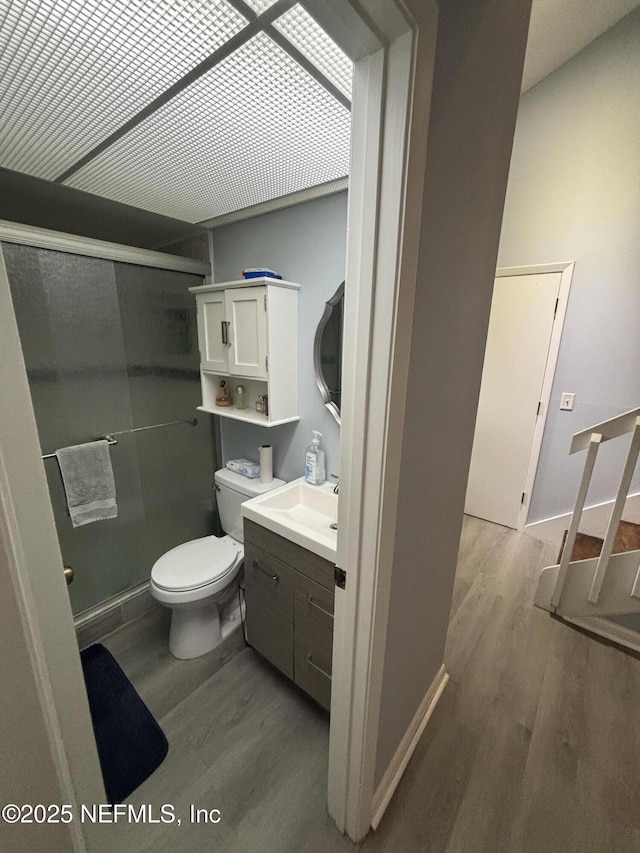 bathroom with walk in shower, vanity, wood-type flooring, and toilet