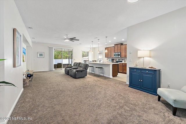 carpeted living room featuring ceiling fan and a textured ceiling