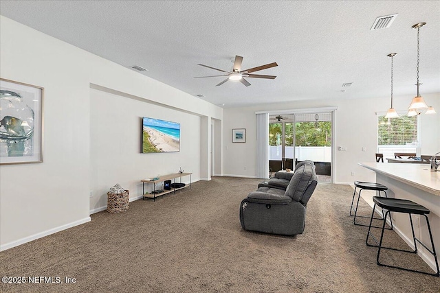 living room with carpet flooring, a textured ceiling, and ceiling fan